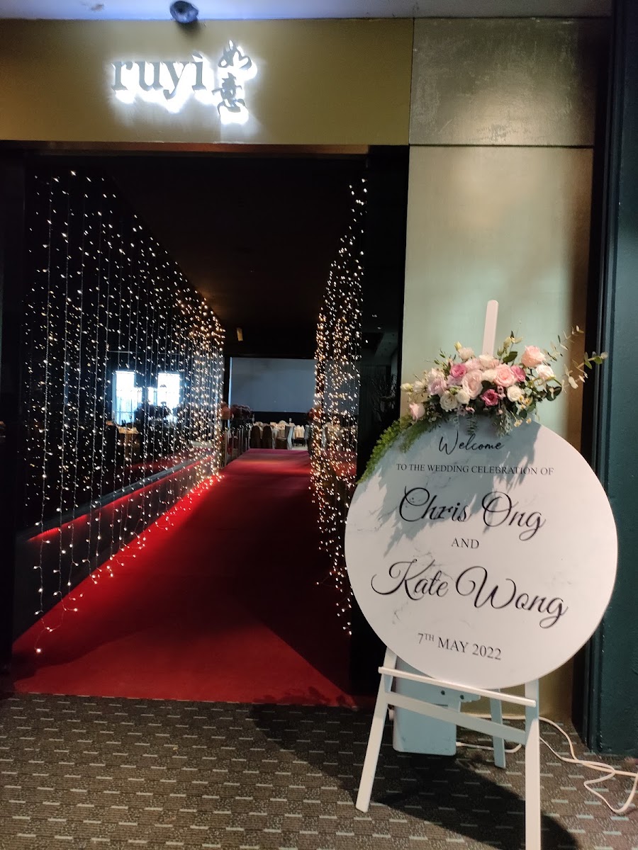 a wedding welcome board with floral arrangement in a restaurant entrance